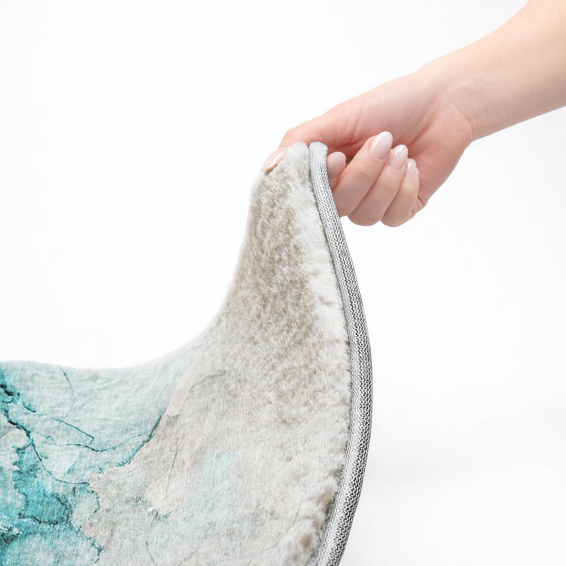 Abstract shag rug edge with gray binding; hand grips the rim