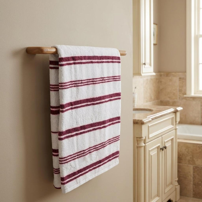 Solid teak towel bar mounted on wall, holding a white towel with burgundy stripes