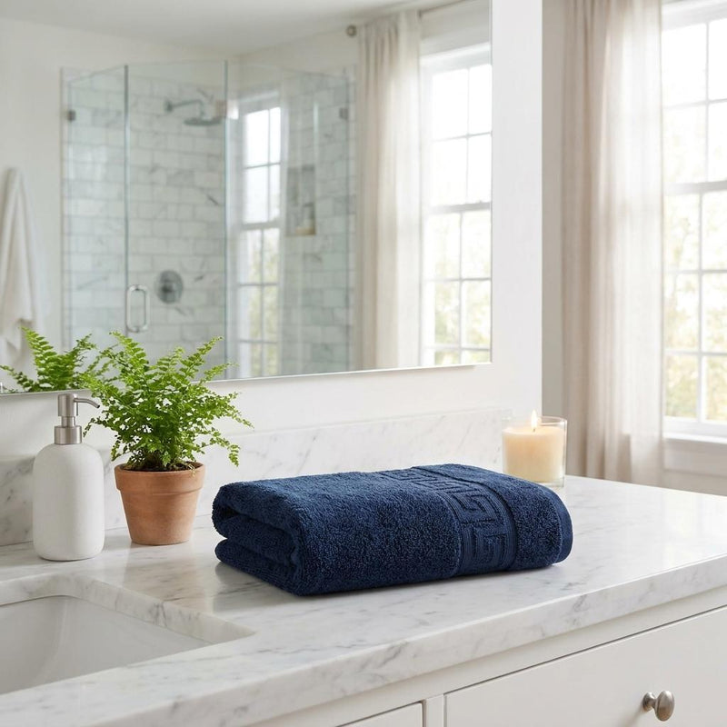 Navy bath towel with Greek key design, folded on bathroom countertop