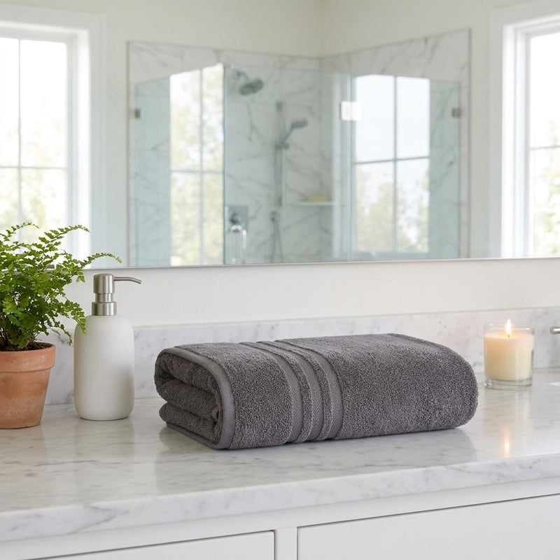 Dark gray bath sheet set rolled on bathroom vanity, striped bands visible