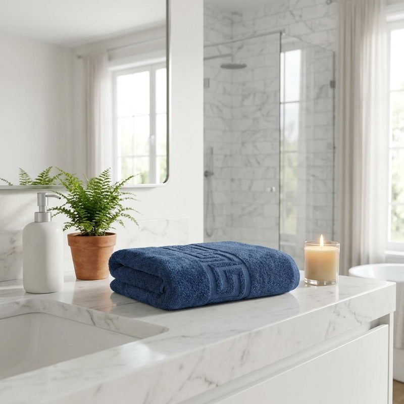 Folded navy bath towels with Greek key pattern on textured terry loop fabric
