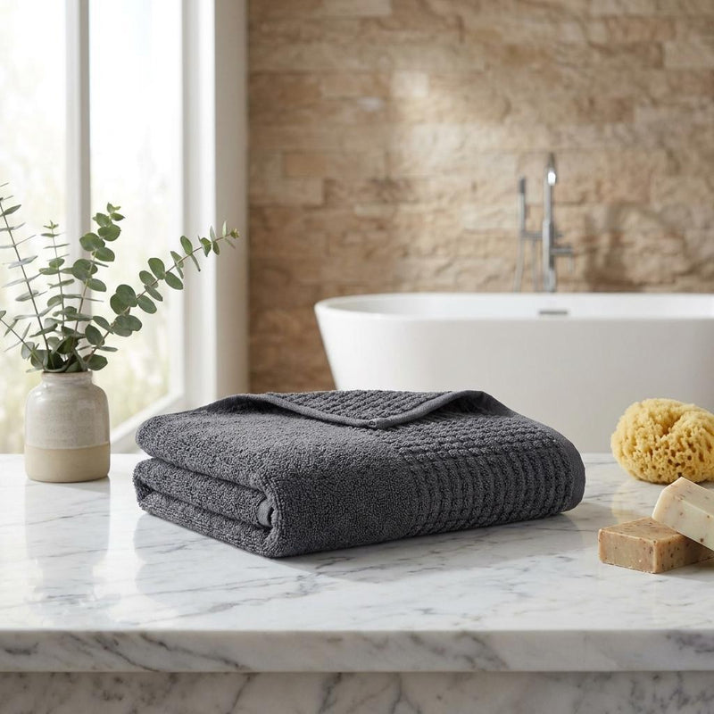 Two dark gray Turkish cotton hand towels folded on countertop, textured polka dot weave