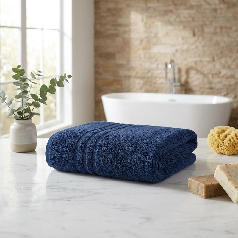 Rolled navy bath towels set of two, plush Turkish cotton, stacked on a counter