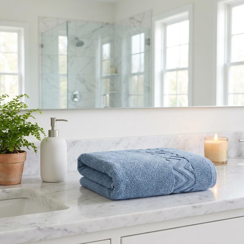 Folded blue Turkish cotton hand towels with geometric chevron pattern, neatly stacked on counter