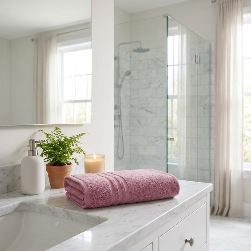 Pink Turkish cotton bath towels folded on a bathroom vanity countertop.