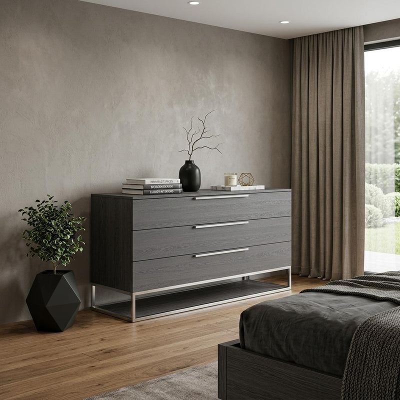 Grey three-drawer dresser with metal bar pulls and open-frame base.