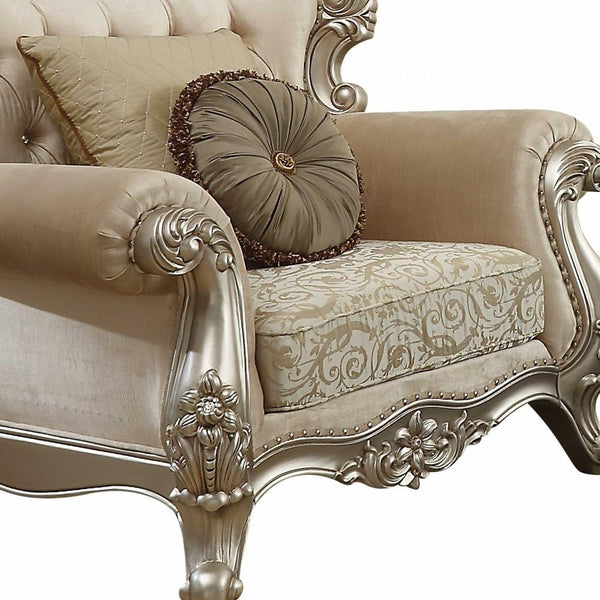 Champagne damask accent chair with ornate silver-tone arms, tufted back, and toss pillows