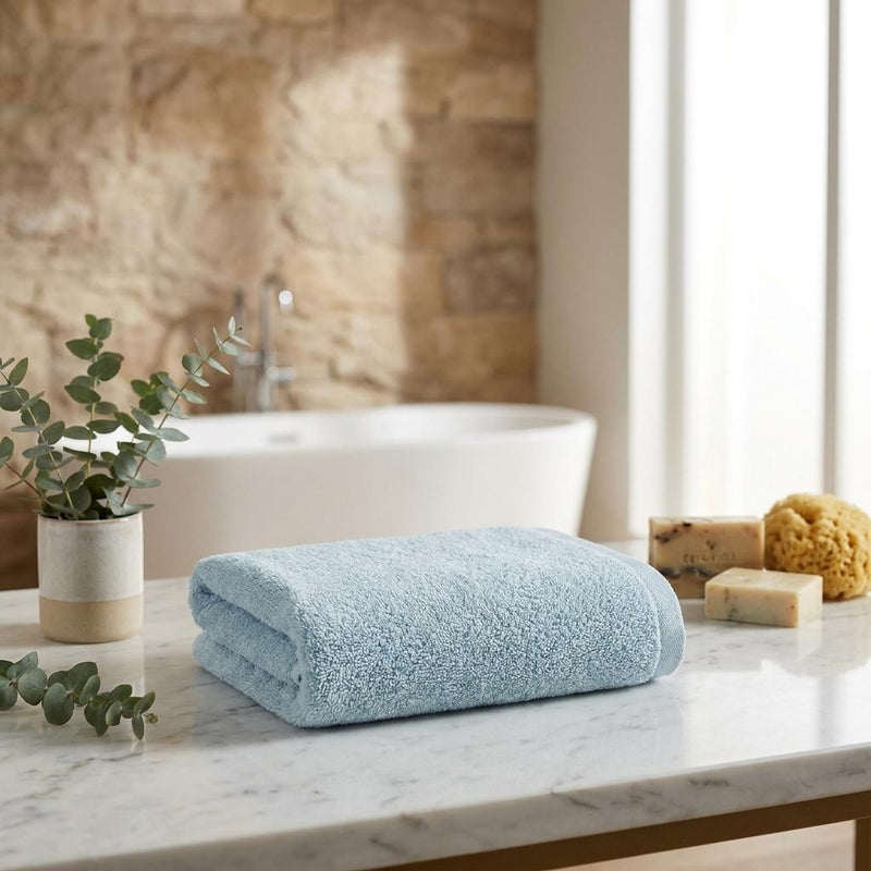 Set of two light blue hand towels on a bathroom countertop, neatly folded.