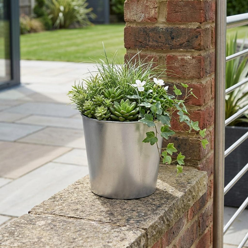 Silver round planter holding small succulents and white flowers