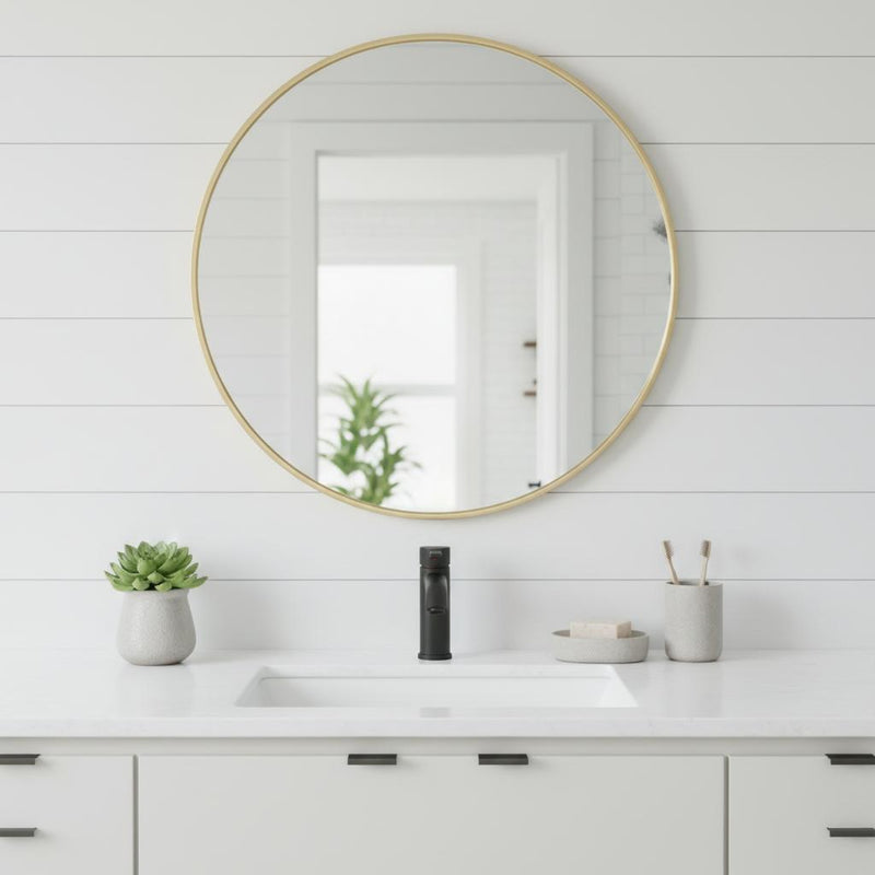 Round bathroom vanity mirror with gold metal frame mounted above sink