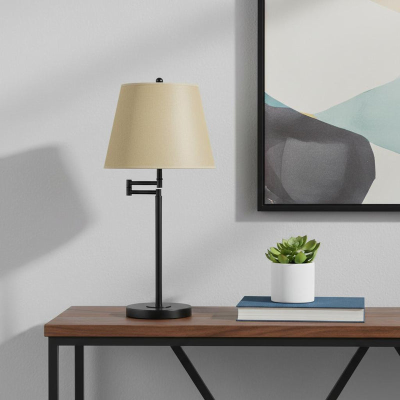 Side-view table lamp with tan empire shade and black metal stem with round base