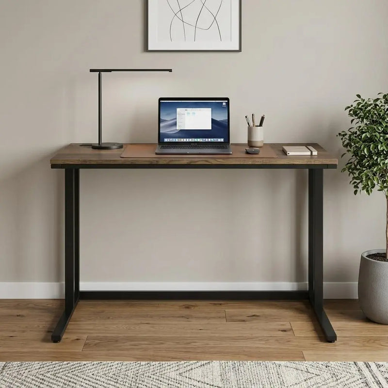 Modern wood desk with black metal legs, featuring a laptop, lamp, and decorative plant, in a minimalist home office setting.
