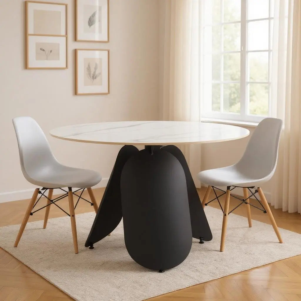 Modern round dining table with white marble top and black base, paired with gray chairs and light wood legs.