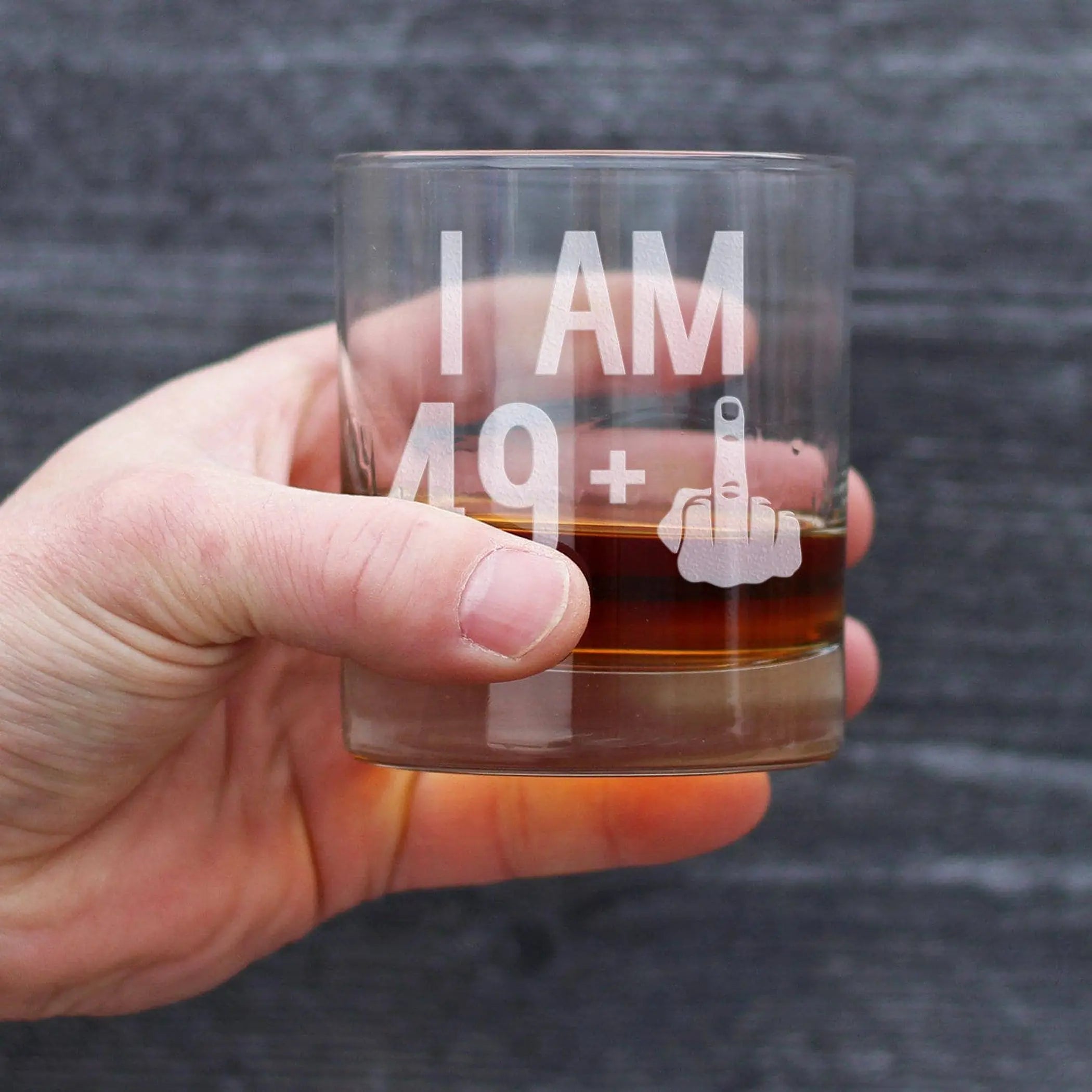 Clear glass whiskey tumbler with etched text "I AM 19+" and middle finger design, perfect for humorous gifts.