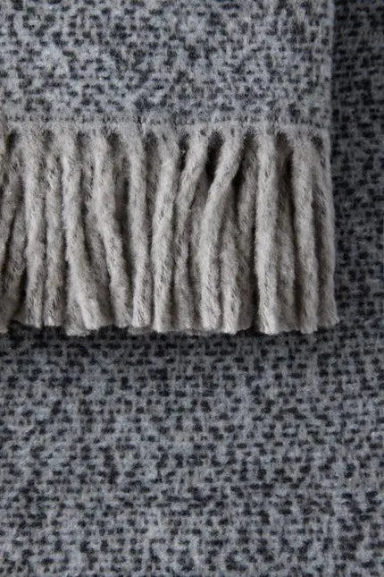 Soft grey fringe-detail throw blanket made of plush fabric, perfect for cozying up in style.