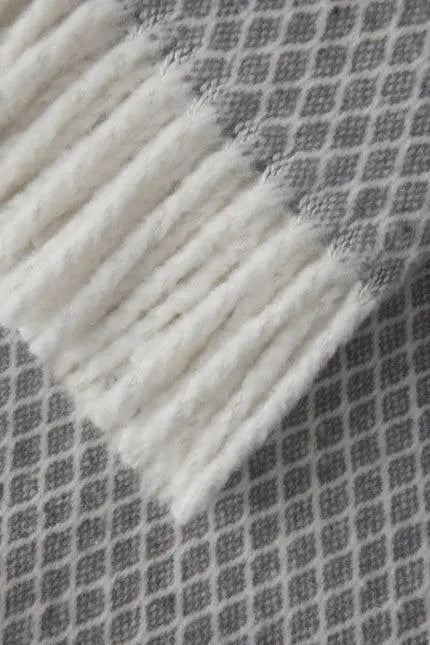 Gray and white patterned throw blanket with soft fringed edges, perfect for home decor and cozy evenings.