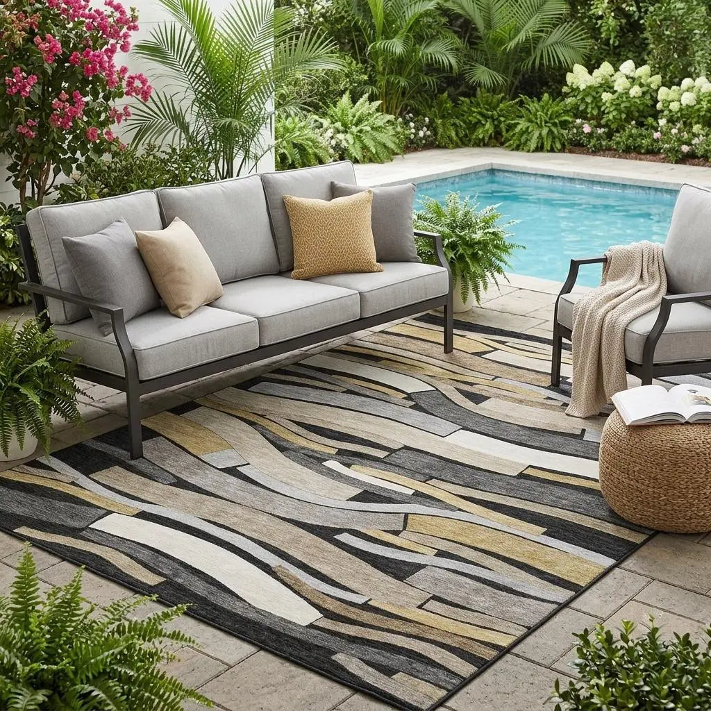 Gray outdoor sofa with throw pillows on a multicolored area rug by a pool, surrounded by lush greenery.