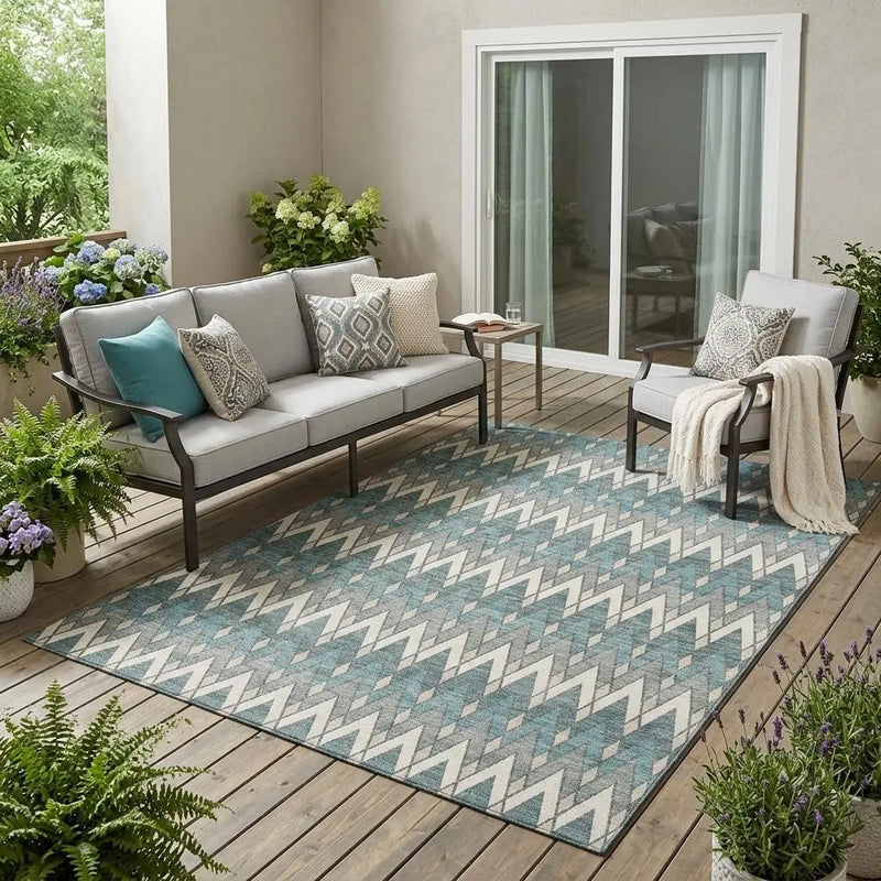 Blue and gray chevron patterned outdoor rug on a patio with modern furniture and potted plants.