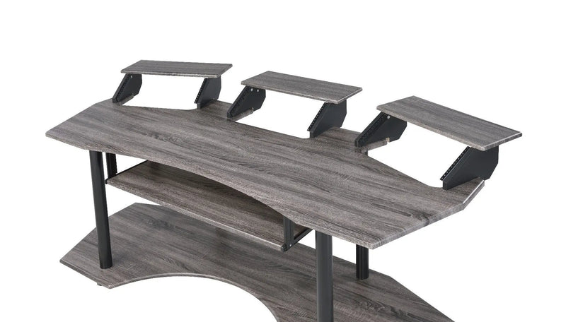 Gray wooden gaming desk with black metal accents and three adjustable monitor stand shelves. Modern and ergonomic design.
