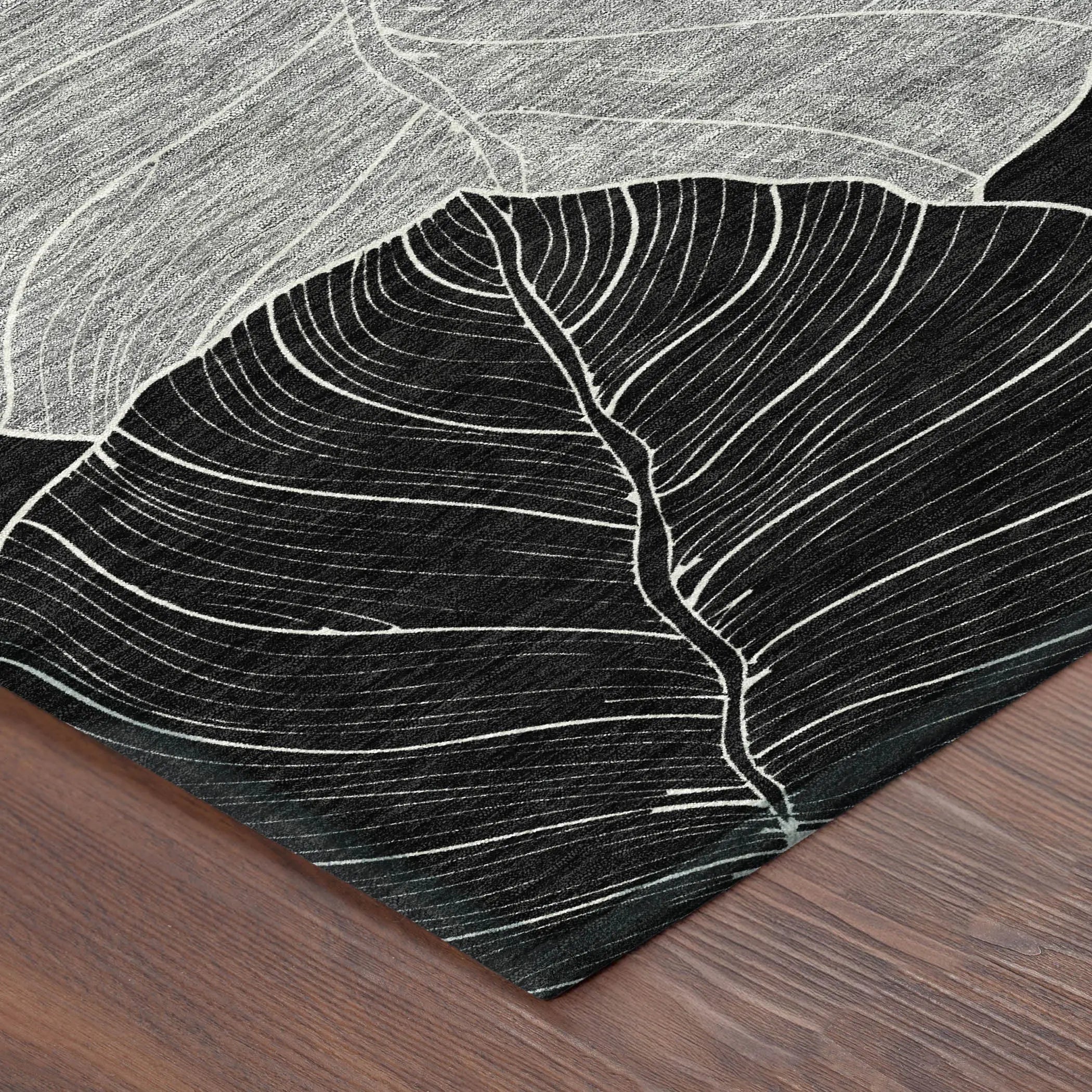 Black and white leaf-patterned area rug, textured fabric, modern style, perfect for contemporary decor.