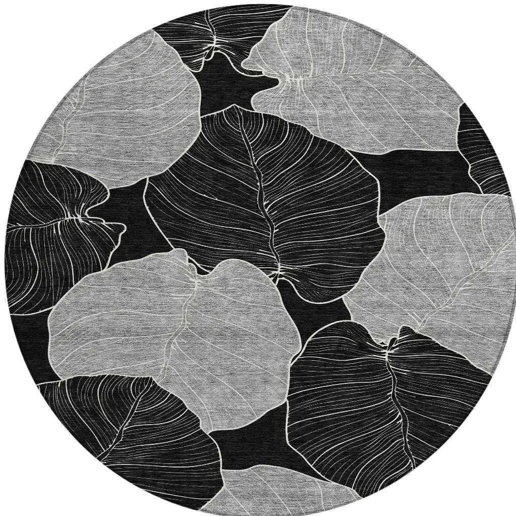 Black and white round area rug with abstract leaf design, featuring textured fabric and a modern aesthetic.
