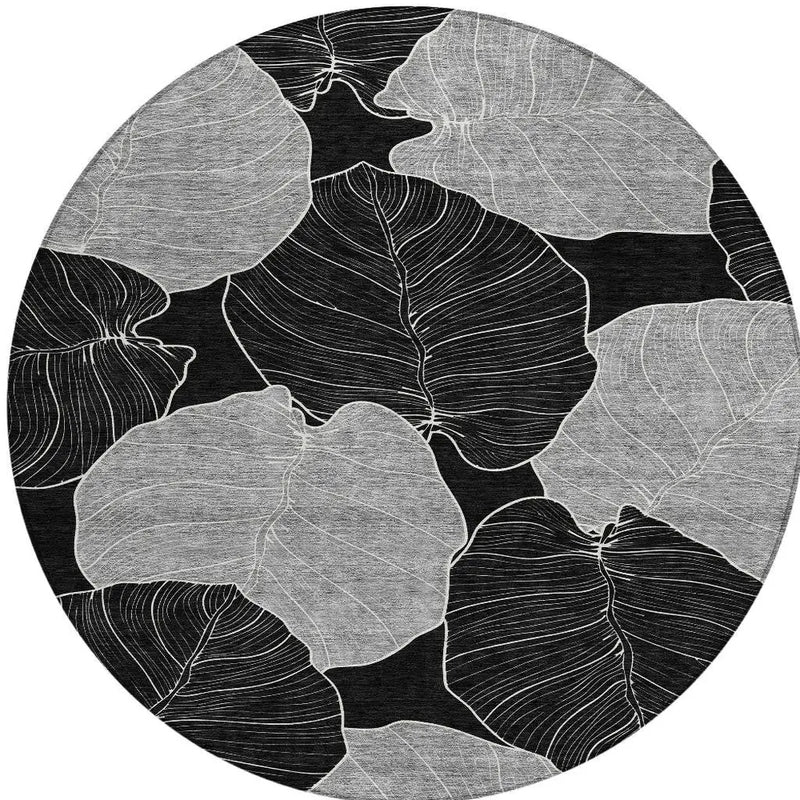 Black and white round area rug with abstract leaf design, featuring textured fabric and a modern aesthetic.