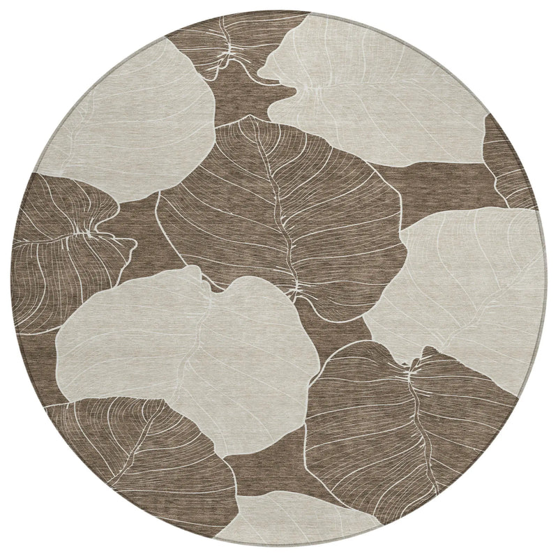Round area rug featuring large beige and brown leaf designs, crafted from durable synthetic fibers for modern decor.