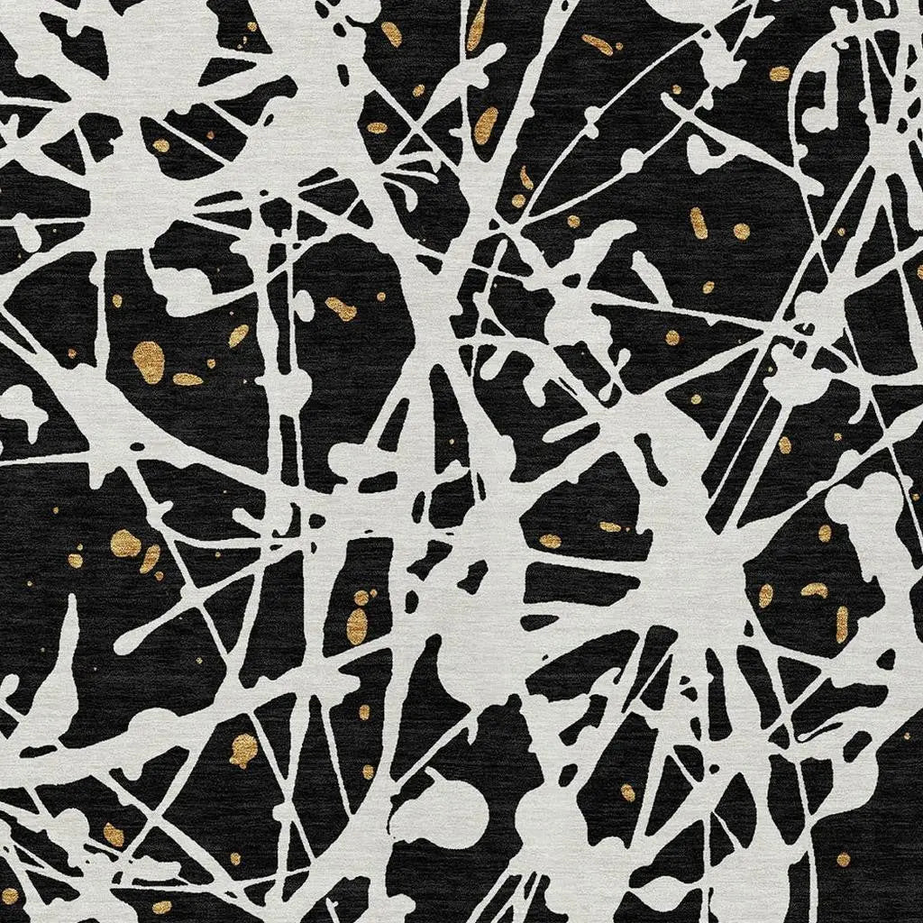 Black and white abstract splatter fabric with gold accents, perfect for modern upholstery or craft projects.