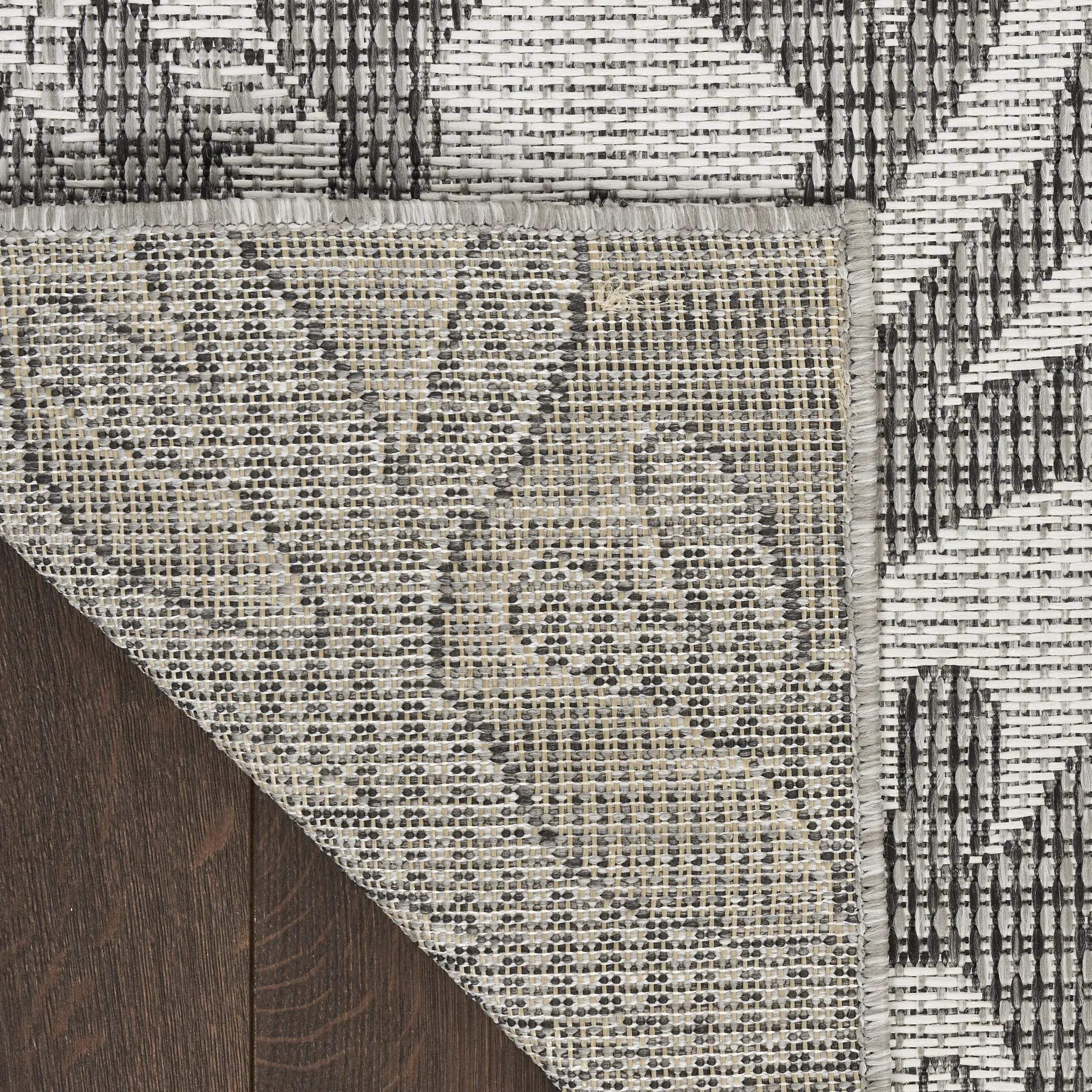 Gray and beige woven area rug with floral pattern, featuring a textured finish and sturdy backing. Perfect for modern decor.