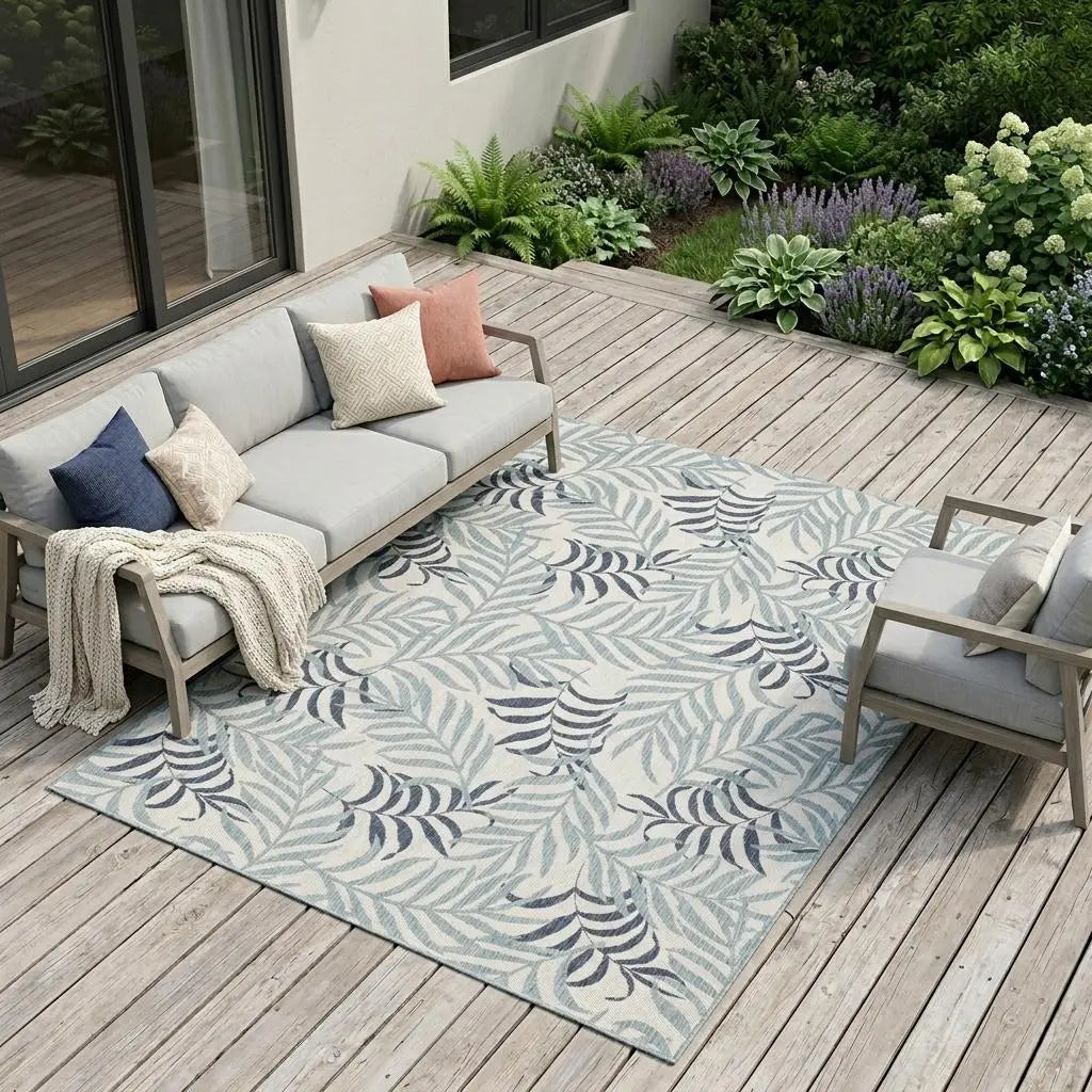 Light blue tropical leaf patterned outdoor rug, crafted from durable fibers, enhancing patio aesthetics.