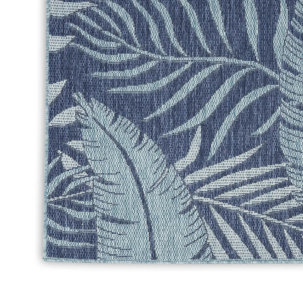 Navy blue and light teal tropical leaf patterned indoor-outdoor area rug in a modern style.