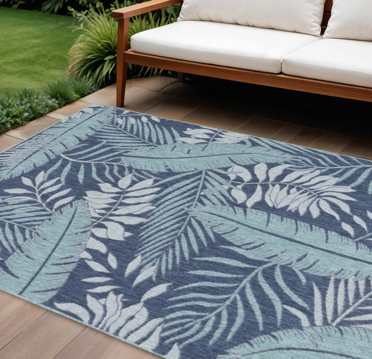 Navy blue tropical leaf area rug with mint green and cream accents, perfect for indoor or outdoor decor.