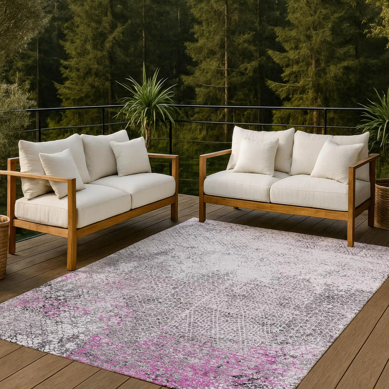 White floral-patterned outdoor rug with gray tones, placed under cream-colored wooden sofas on a deck.