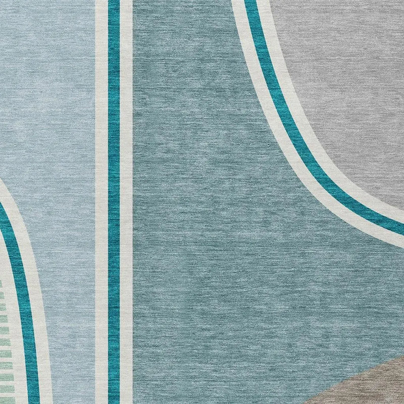 Abstract area rug in soft blue, grey, and teal color palette; modern design with geometric patterns and plush texture.