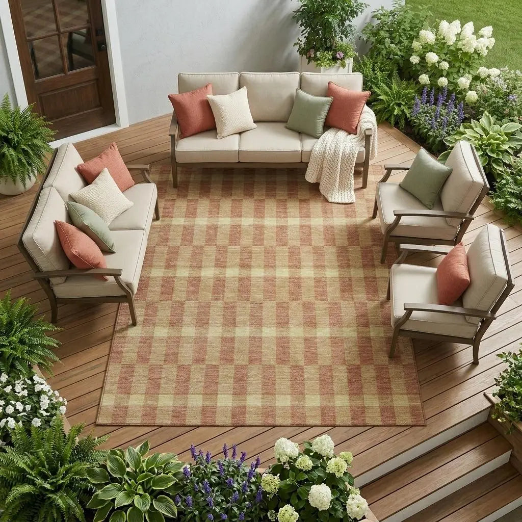 Beige outdoor seating set with coral and green cushions on a checkered rug, surrounded by lush greenery.