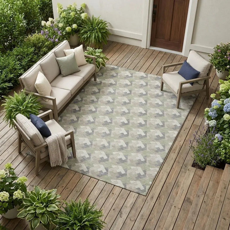 Light gray geometric outdoor rug on wood patio, surrounded by green plants and modern chairs and sofa. Ideal for stylish decor.