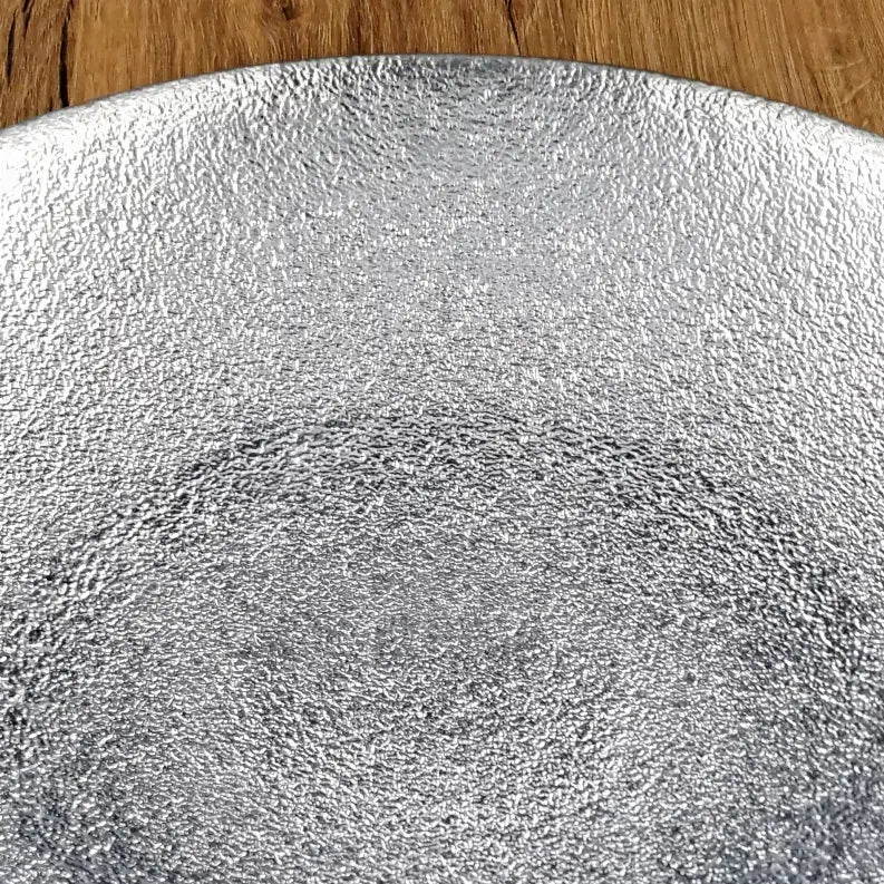 Silver textured serving plate on wooden background, perfect for elegant dining settings and modern home decor.