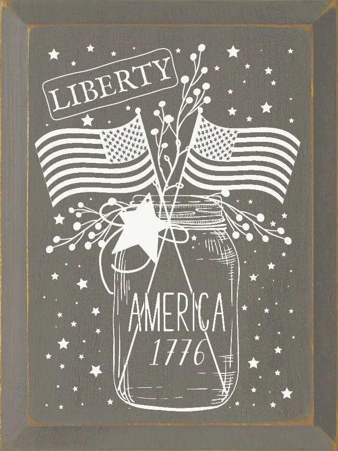 Rustic gray wood sign with white mason jar, American flags, and "Liberty America 1776" text, perfect for patriotic decor.