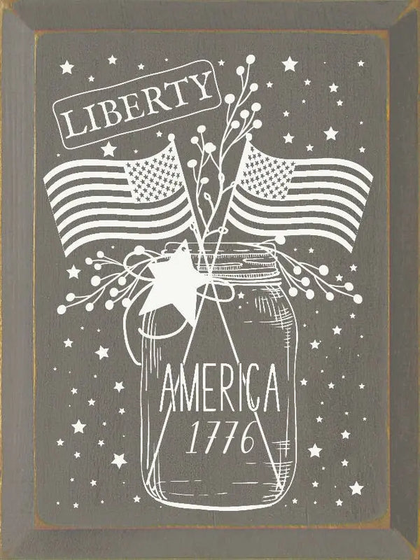 Rustic gray wood sign with white mason jar, American flags, and "Liberty America 1776" text, perfect for patriotic decor.