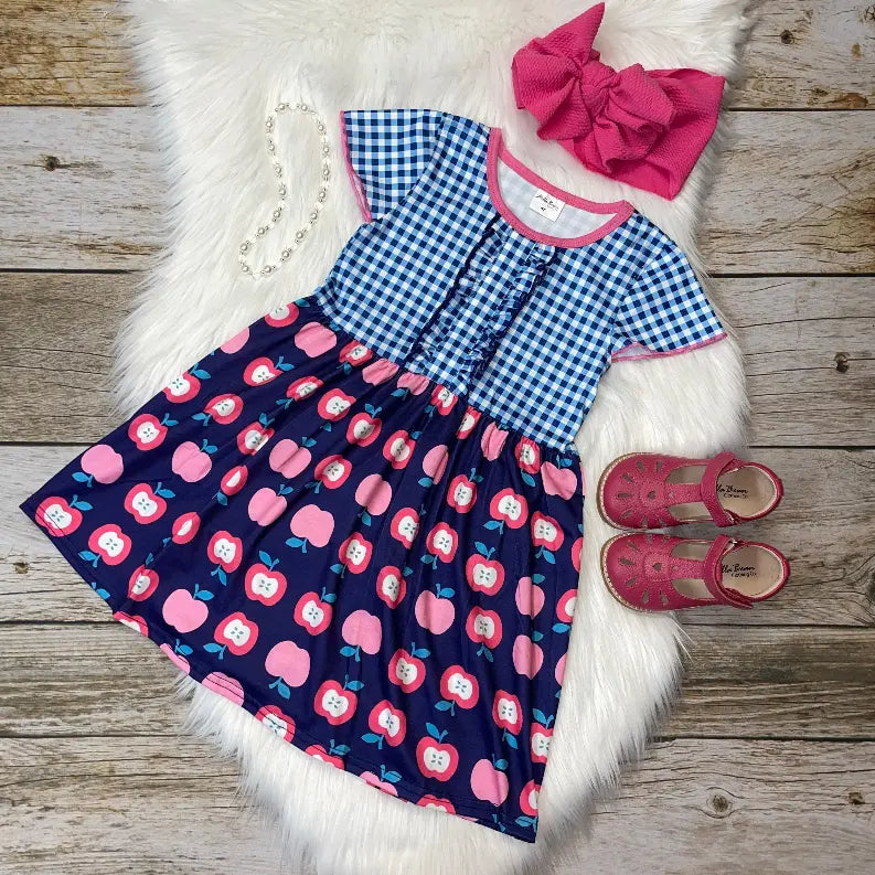 Blue and pink apple-print dress with gingham top, paired with a pink bow headband and matching shoes. Perfect for summer!