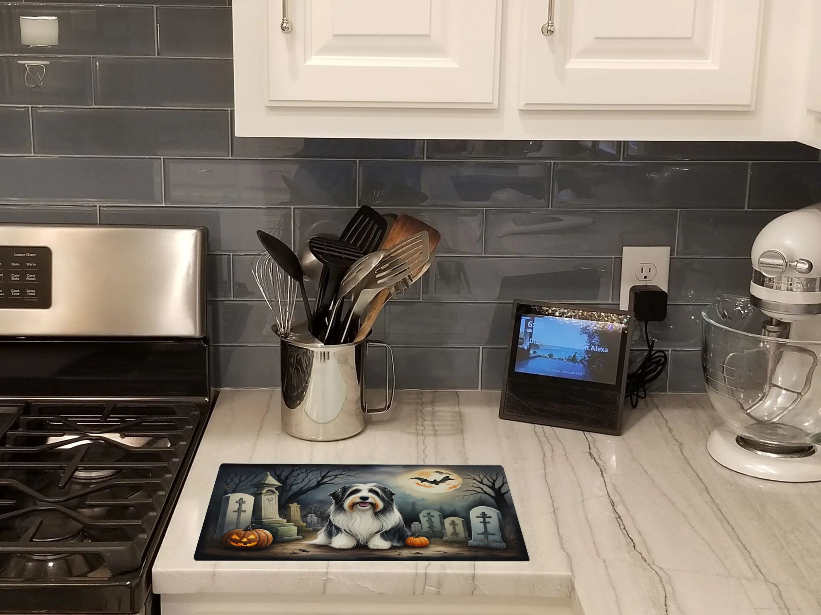 Halloween-themed kitchen mat featuring a fluffy dog, pumpkins, and graveyard design, set on a marble countertop.