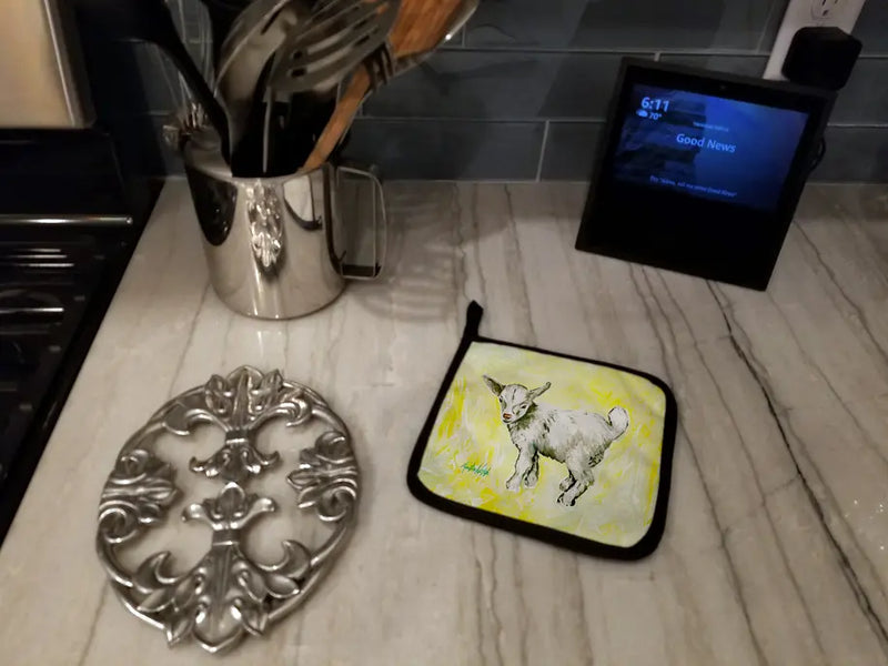 Colorful hand-painted pot holder featuring a playful goat design, set against a sleek marble countertop.