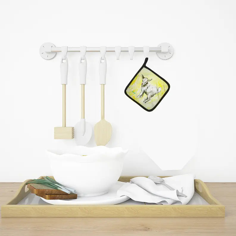 White ceramic bowl and wooden utensils on a natural wood tray with a colorful rabbit-themed pot holder.
