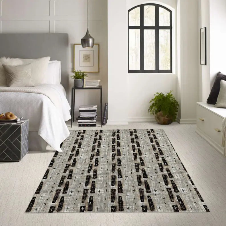 Elegant grey and black geometric area rug in a cozy bedroom setting, made of durable synthetic fibers.