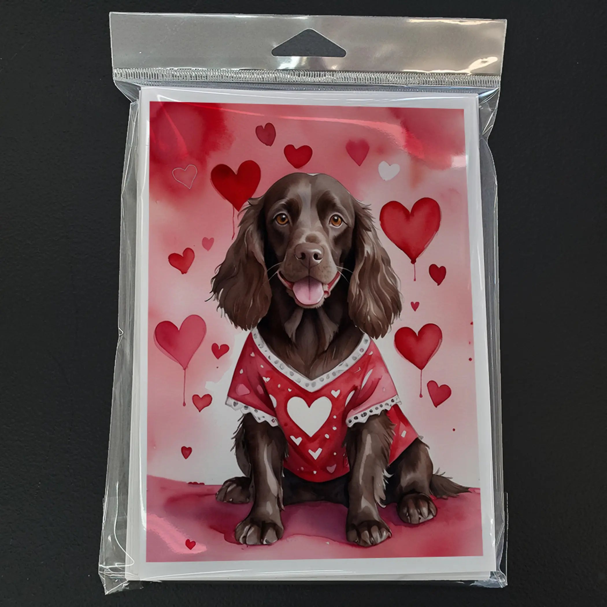 Chocolate brown dog wearing a red heart-patterned sweater on a pink heart backdrop, perfect for Valentine's Day.