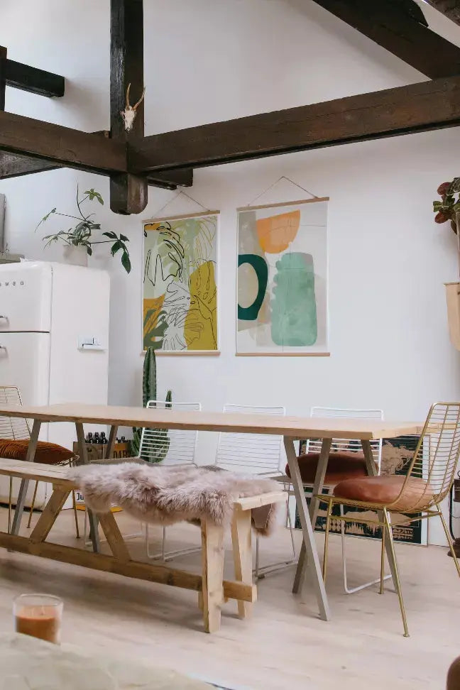 Cozy dining area featuring a wooden table, metal chairs, and vibrant wall art in green and yellow hues.
