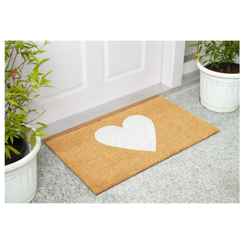 Heart-shaped white design on a natural coir doormat, perfect for welcoming guests. Ideal for indoor or outdoor use.