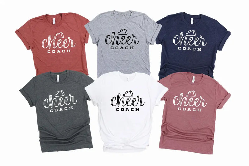Set of six "Cheer Coach" t-shirts in colors: gray, navy, white, maroon, green, and black. Soft cotton blend, casual style.
