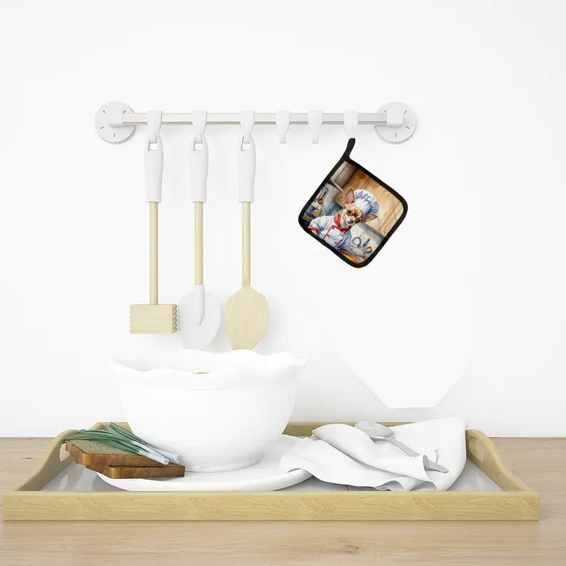 Colorful chef apron hanging on a white rack, with wooden kitchen utensils and a decorative bowl on a natural wood tray.