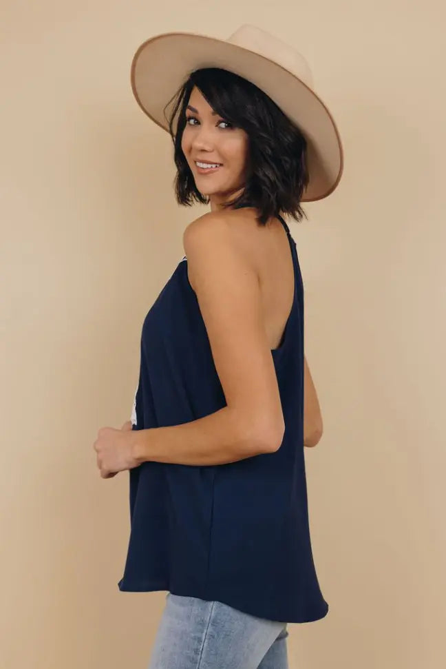 Navy blue sleeveless top with a relaxed fit, paired with a wide-brimmed beige hat and light denim jeans.